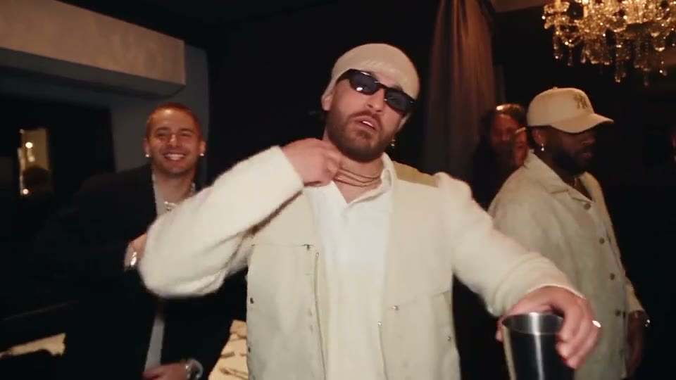A guy in a cream suit and sunglasses takes Drake's spot: the point, the hand flick and the wave.